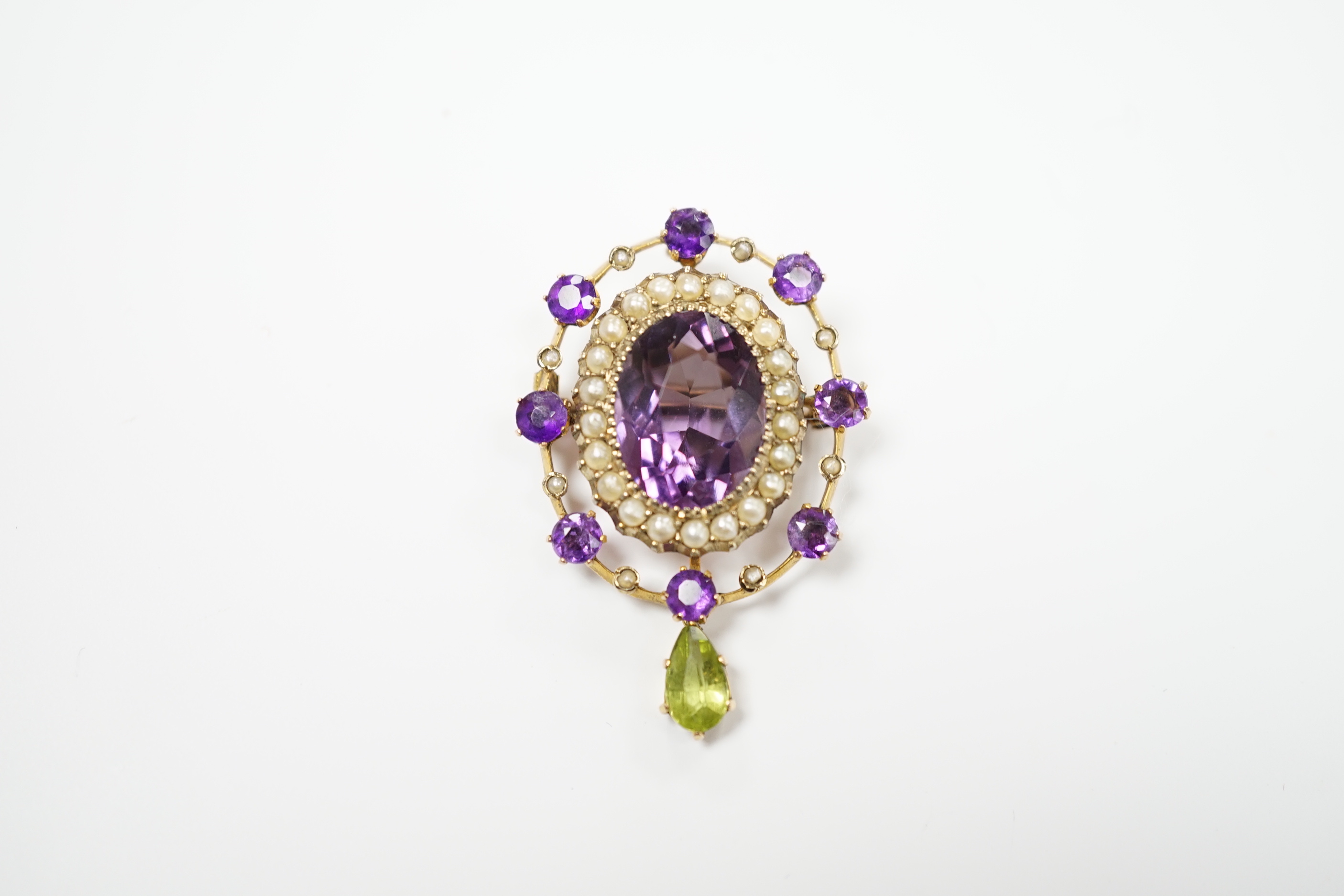 An early 20th century yellow metal, amethyst, peridot and seed pearl cluster set drop pendant brooch, 35mm, gross weight 4.9 grams.
